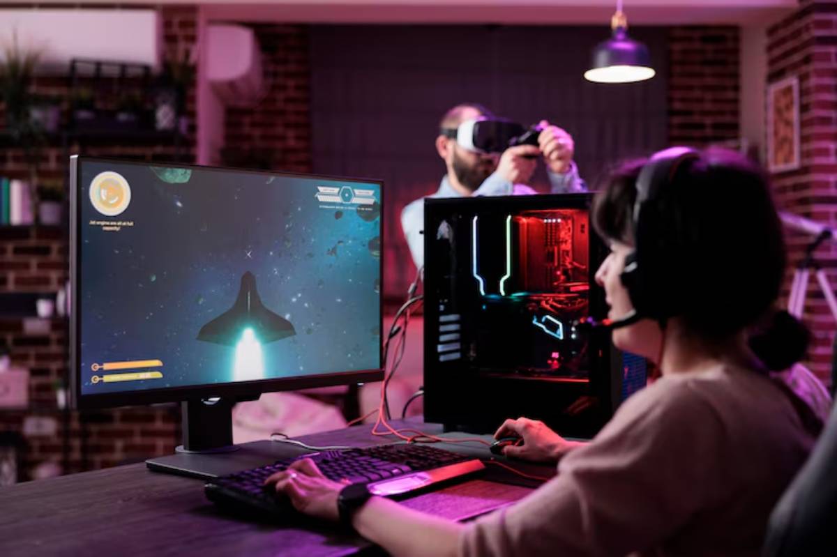 A gamer plays a space adventure on a monitor, with a colorful gaming PC and keyboard in a cozy, modern gaming setup.