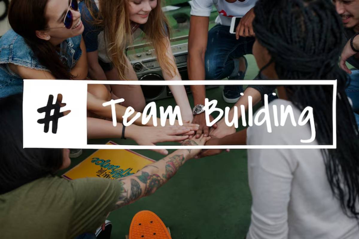 A group of individuals joining hands in a team-building activity, surrounded by colorful materials and a boombox. #TeamBuilding