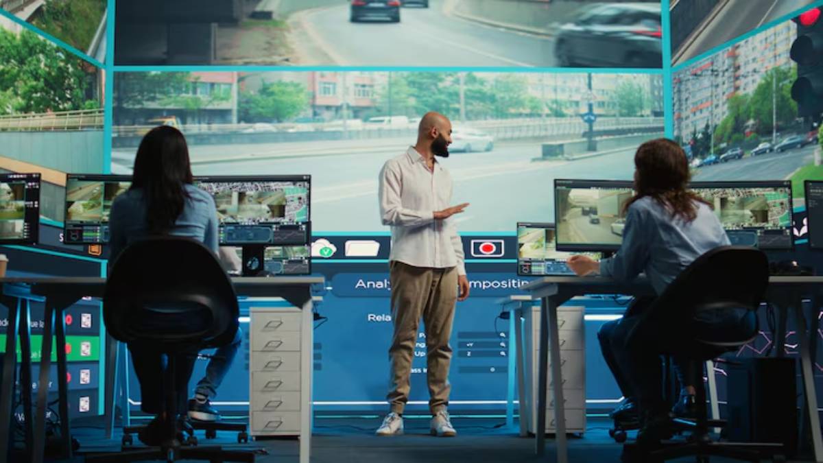 A modern control room with three individuals analyzing traffic footage on multiple screens and large displays in the background.