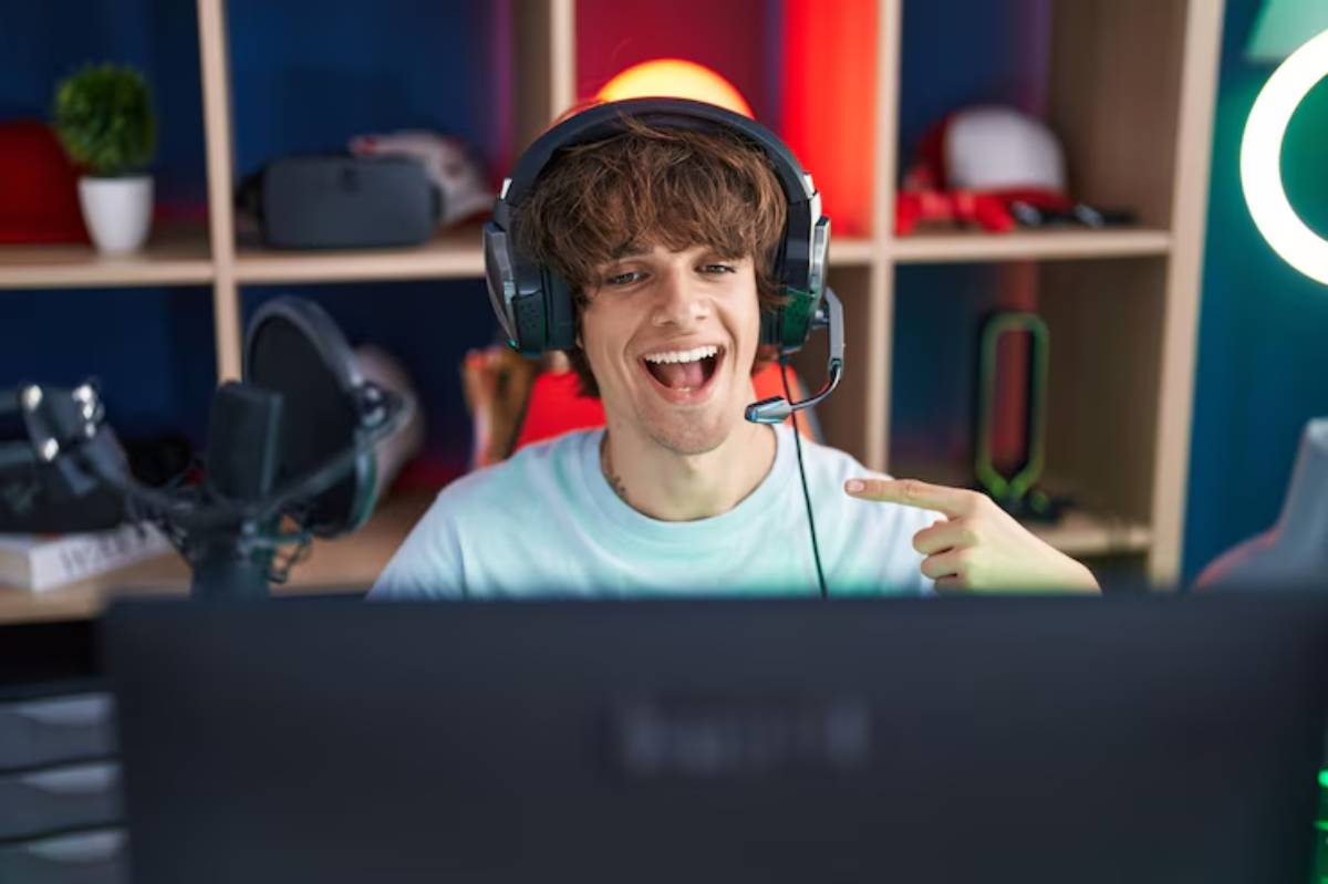 A gamer wearing a headset points at the screen, surrounded by gaming accessories and a colorful background.